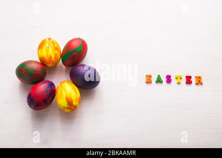 Lettres en bois multicolores composant les mots Happy easter et œufs colorés décoratifs sur fond blanc. Banque D'Images