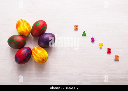 Lettres en bois multicolores composant les mots Happy easter et œufs colorés décoratifs sur fond blanc. Banque D'Images