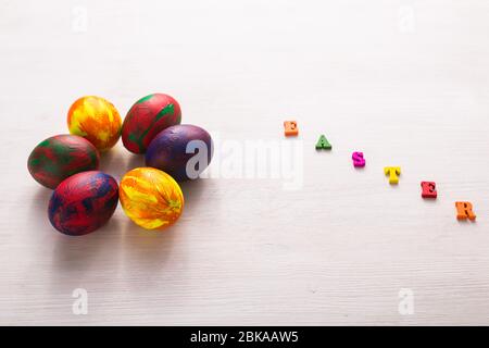 Lettres en bois multicolores composant les mots Happy easter et œufs colorés décoratifs sur fond blanc avec espace de copie. Banque D'Images