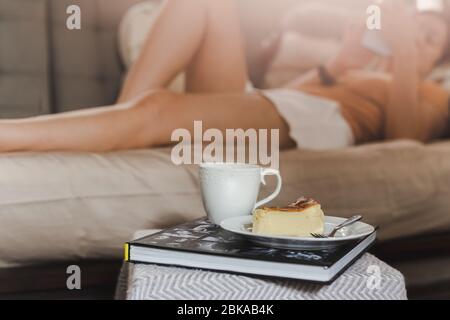 Femme utilisant un téléphone cellulaire avec le cheesecake brûlé basque et le café sur la table. Banque D'Images