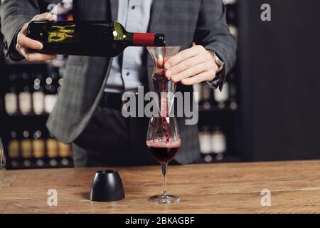Sommelier versant du vin rouge dans un verre de décanteur pour faire boire de l'aération Banque D'Images