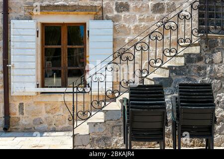 Maison authentique avec un mur en pierre et une belle fenêtre avec volets, avec un escalier latéral, dans les chaises en toile de fond. Perast, LUN Banque D'Images