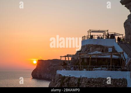 Coucher de soleil sur les terrasses à Cova d'en Xoroi, un bar et une discothèque situé dans les grottes naturelles, Cala en porter, Minorque, Espagne Banque D'Images