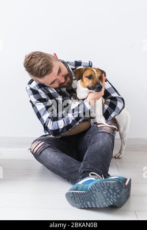 Concept de propriétaire d'animaux de compagnie - attrayant homme gai dans une chemise à carreaux tient l'animal préféré. Joyeux barbu avec son Jack russell terrier Banque D'Images