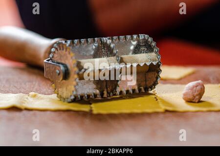 Le couteau à pâtes est sur une table en bois prête à dimensionner les pâtes fraîches pour la tortellini. Il y a également la quantité de remplissage appropriée. Banque D'Images