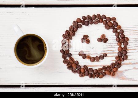 Tasse de café chaud et de haricots en forme de visage souriant. Banque D'Images