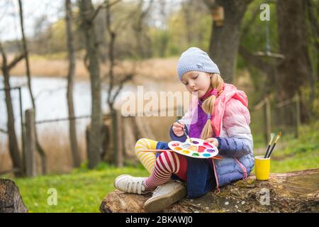 Petite fille peint au printemps sur la nature Banque D'Images