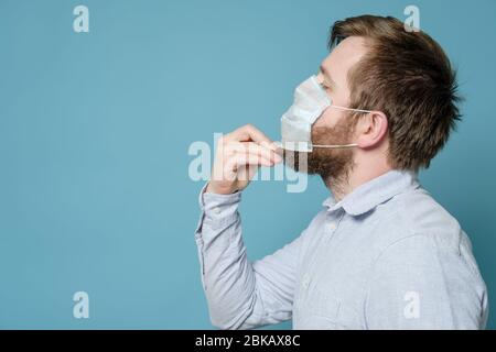 Homme barbu dans un masque médical, qui ne s'adapte pas parfaitement à cause du visage non rasé. Espace de copie. Concept de sécurité pendant une pandémie. Banque D'Images