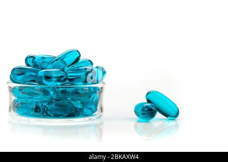 Gros plan des capsules de gel doux médical bleu sur fond blanc - suppléments médicaux Banque D'Images