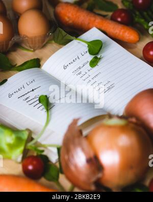 Ordinateur portable ouvert entouré de légumes. Liste d'épicerie avec des légumes autour. Il y a une liste de magasins avec des légumes qui l'entourent. Il y a des épiceries Banque D'Images