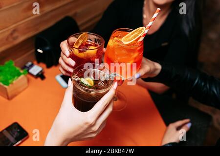 Trois verres à encrage pour filles avec cocktail alcoolique d'été. Cocktail Apérol Spitz. Boissons alcoolisées à base de table avec glaçons et oranges. Banque D'Images