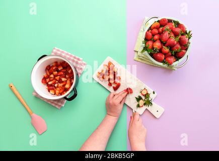 Femme préparant de la confiture de fraises sur fond sans couture duotone. Plat avec la fabrication de marmelade. Trancher les fraises pour faire de la confiture. Banque D'Images