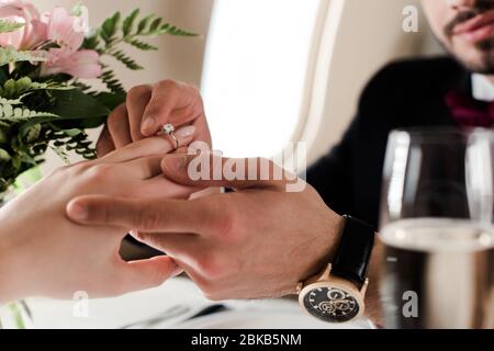 vue réduite de l'homme mettant l'anneau de mariage sur la femme tout en faisant la proposition de mariage dans l'avion Banque D'Images
