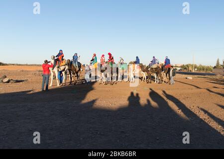 Groupe de touristes se préparer pour une balade en Camel avec les vêtements longs traditionnels et la couverture de tête à Marrakech, Maroc, Afrique du Nord Banque D'Images