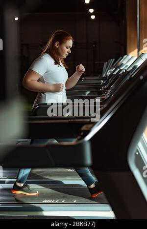 foyer sélectif de la fille en surpoids focalisée courir sur le tapis roulant dans la salle de gym Banque D'Images