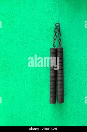 Arme Nunchaku isolée sur fond vert. Formation nunchaku noir pour débutant. Équipement d'arts martiaux Hot Tactical Gear. Banque D'Images