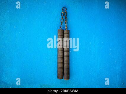 Arme Nunchaku isolée sur fond bleu. Formation nunchaku noir pour débutant. Équipement d'arts martiaux Hot Tactical Gear. Banque D'Images