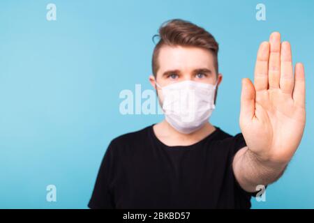 Beau homme montrant la butée de geste. Photo d'un homme en bonne santé portant un masque protecteur contre les maladies infectieuses et la grippe. Soins de santé, Covid-19 et Banque D'Images