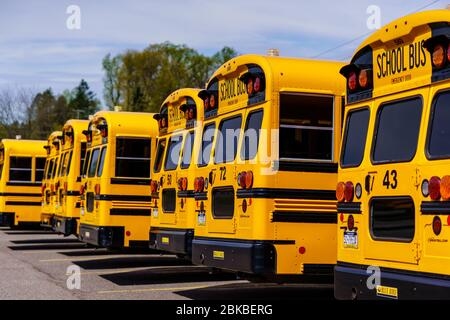 Mohnton, PA / USA - 2 mai 2020: Une vue arrière d'une ligne de bus scolaires garés dans beaucoup de Berks County, Pennsylvanie. Banque D'Images