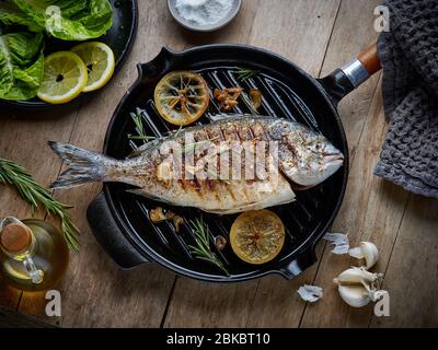 poisson épicé sur la poêle à griller sur la table de cuisine en bois, vue sur le dessus Banque D'Images