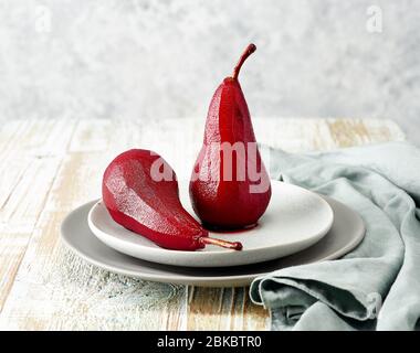 Assiette de poires pochée dans du vin rouge sur table en bois Banque D'Images