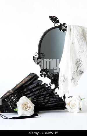 Miroir noir vintage avec couverture en dentelle blanche et roses en papier et ventilateur à main sur fond blanc. Funérailles, condoléances et concept de chagn Banque D'Images