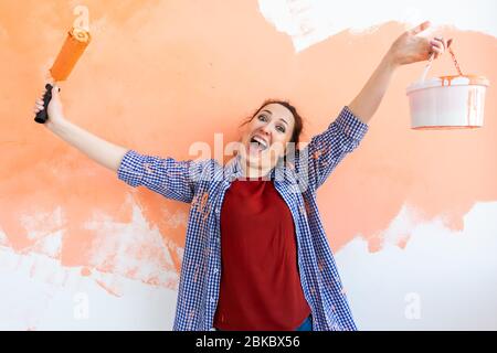 Drôle femme peinture mur dans son nouvel appartement. Rénovation et redécoration. Banque D'Images