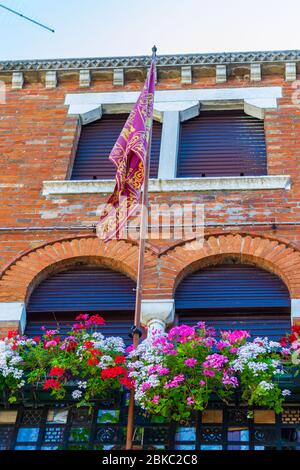 Bâtiment historique à Venise avec drapeau vénitien et pots de fleurs colorées au balcon, Venise, Vénétie, Italie Banque D'Images