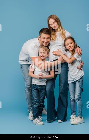 un mari et des enfants heureux embrassent la femme enceinte en bleu Banque D'Images