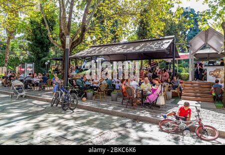 Une des rues piétonnes les plus populaires de la ville avec des arbres à Tirana, (rue Murat Toptani) les gens se reposent dans un café extérieur au bord de la rue. Banque D'Images