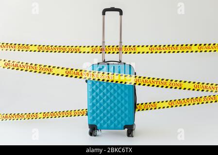 valise bleue en ruban de sécurité jaune et noir pour avertissement de danger avec illustration de zone de quarantaine sur concept blanc de coronavirus Banque D'Images