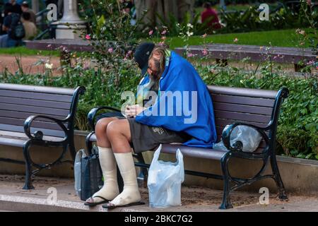 Un homme sans domicile sur un banc à Hyde Park, Sydney Banque D'Images