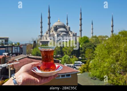 Tasse de main de femme avec thé turc traditionnel devant la mosquée bleue, alias Sultanahmet Camii à Istanbul, Turquie. Principales attractions d'Istanbul. Banque D'Images