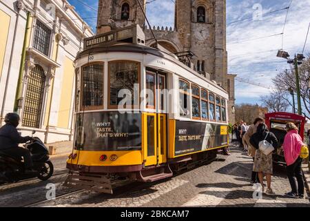 Lisbonne, Portugal - 8 mars 2020: Les touristes qui voyagent le célèbre tramway jaune 28 en face de la cathédrale de Lisbonne Banque D'Images