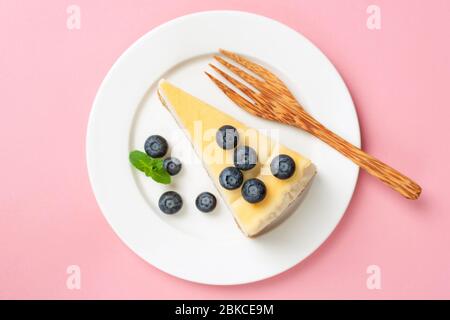 Tranche de Cheesecake avec bleuets sur fond rose, vue sur le dessus de la table Banque D'Images