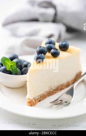 Tranche de cheesecake surmontée de bleuets sur une plaque blanche. Un délicieux cheesecake classique de style New york Banque D'Images