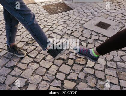 Appui sur le pied. Nouvelle salutation nouvelle pour éviter la propagation du coronavirus. Deux femmes amis se rencontrent dans une rue britannique. Au lieu de saluer avec un hug ou Banque D'Images