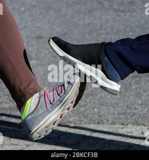 Appui sur le pied. Nouvelle salutation nouvelle pour éviter la propagation du coronavirus. Deux femmes amis se rencontrent dans une rue britannique. Au lieu de saluer avec un hug ou Banque D'Images