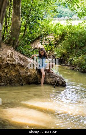 Jeune fille jouant dans un ruisseau boisé à Wowo's, un camping familial à Sussex Banque D'Images