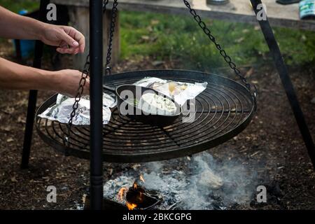 Cuisine sur un feu de camp sur un barbecue suspendu à Wowo's, un camping familial de Sussex Banque D'Images