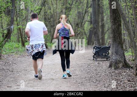 Couple en train de courir dans un parc de printemps pendant la quarantaine, vue arrière. Concept d'entraînement, coureurs, minceur Banque D'Images