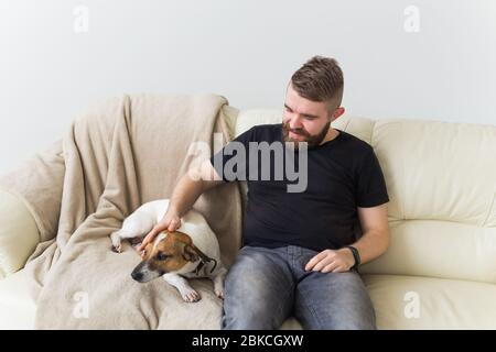 Attrayant gai caucasien mâle dans une chemise décontractée assis sur le canapé animal préféré. Joyeux barbu avec son Jack russell terrier. Propriétaire de l'animal Banque D'Images