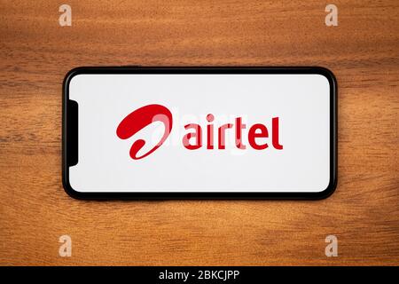 Un smartphone affichant le logo Bharti Airtel repose sur une table en bois ordinaire (usage éditorial uniquement). Banque D'Images