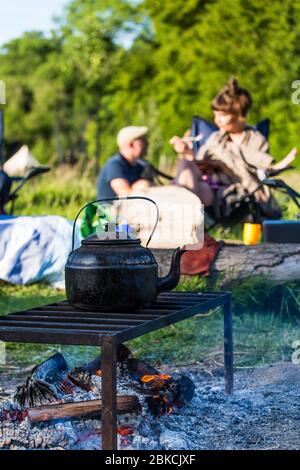 Faire bouillir une énorme bouilloire noircie pour une tasse de thé un feu ouvert pendant le camping dans le Kent, Royaume-Uni Banque D'Images