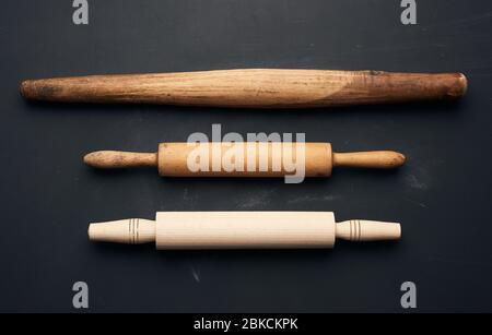 trois types de goupilles à roulettes en bois pour faire rouler la pâte sur fond noir, ustensiles neufs et très anciens, vue de dessus Banque D'Images