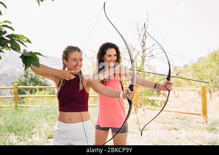 Tir à l'arc. Deux jeunes femmes qui pratiquent le tir à l'arc sur le terrain. Sport, concept récréatif. Banque D'Images