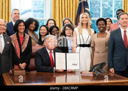 Le président Donald J. Trump, accompagné de la conseillère Ivanka Trump et de membres du Cabinet, signe le mémorandum présidentiel sur la sécurité nationale le 7 février 2019, pour lancer l'Initiative pour le développement et la prospérité mondiales des femmes dans le Bureau ovale. Banque D'Images
