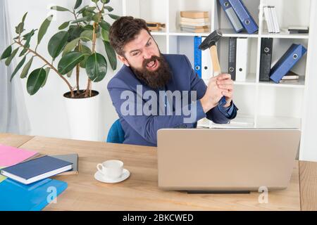 Crier. Résoudre certains problèmes d'affaires. Ordinateur est à la traîne. Homme d'affaires ou Manager en colère avec un marteau à traîner. Homme d'affaires agressif au bureau. Raisons du retard de l'ordinateur. Routine de bureau de haine. Banque D'Images