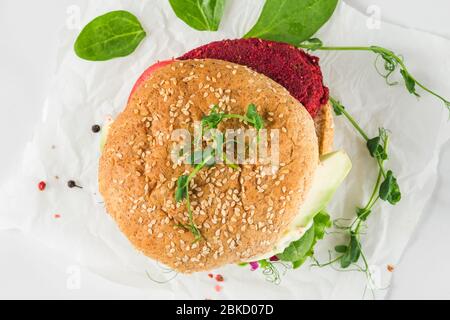 Hamburger Veggie avec betterave et avocat sur table en marbre blanc. Cuisine végétalienne saine. Vue de dessus Banque D'Images