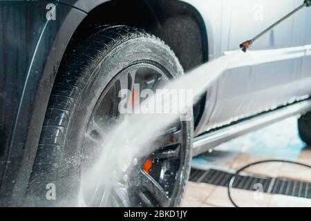 Lavage de voiture en soi. Les roues à l'aide de nettoyage de l'eau sous pression. Banque D'Images